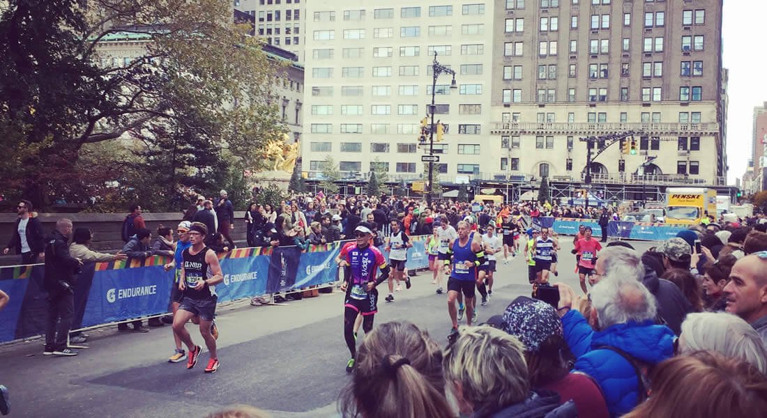 A crowd is watching a running marathon through the streets of New York City