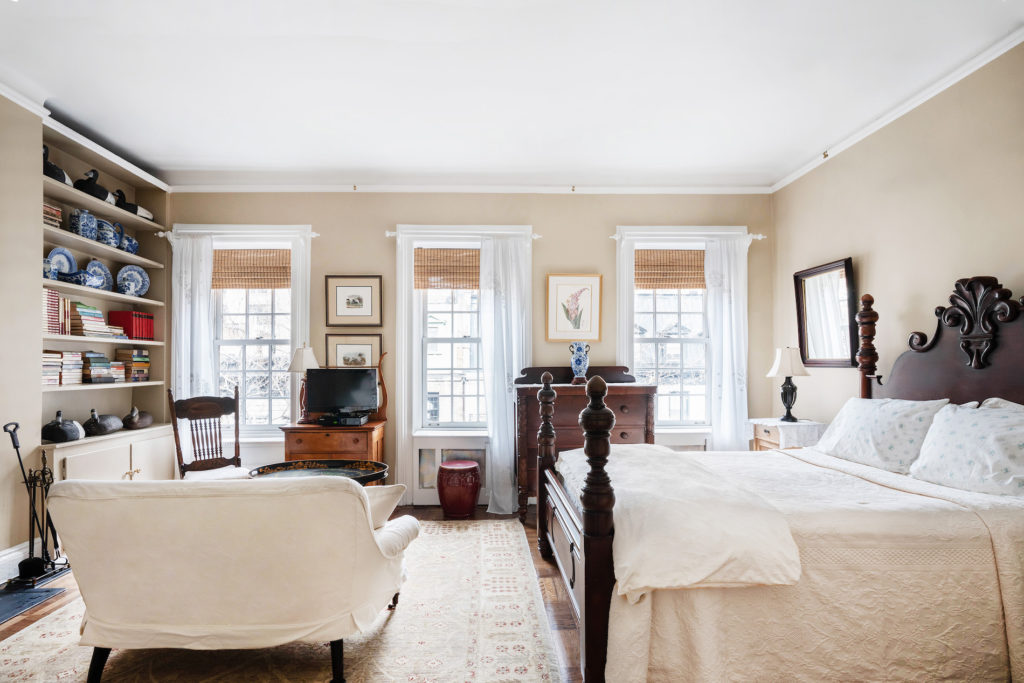 four poster bed with white bedspread and white loveseat