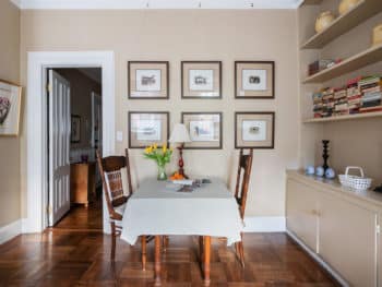dining table with white tablecloth and 6 prints on the wall