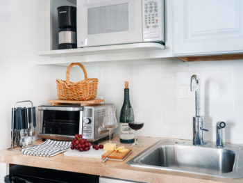 Kitchenette with toaster oven, microwave, drip coffee maker and butcher block counter top. Grapes, cheese and wine on the counter.