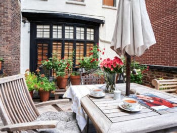 Terrace with wood decking. Teak chairs, large umbrella and plantings.