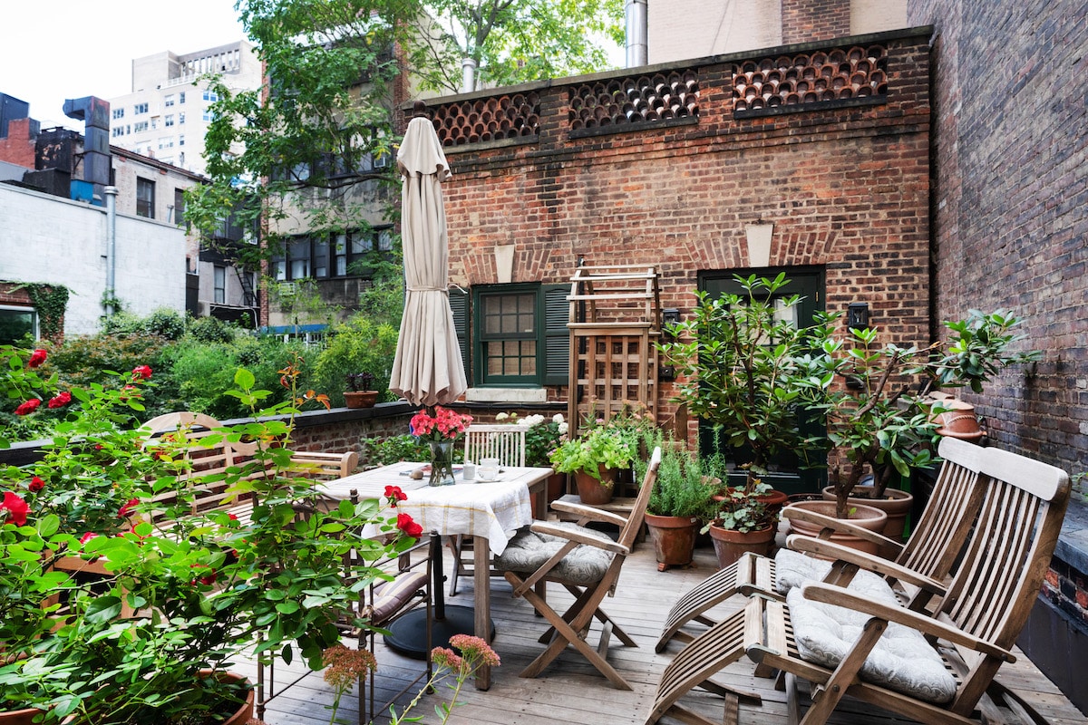 Terrace with teak table, chairs, large umbrella and lounge chairs.