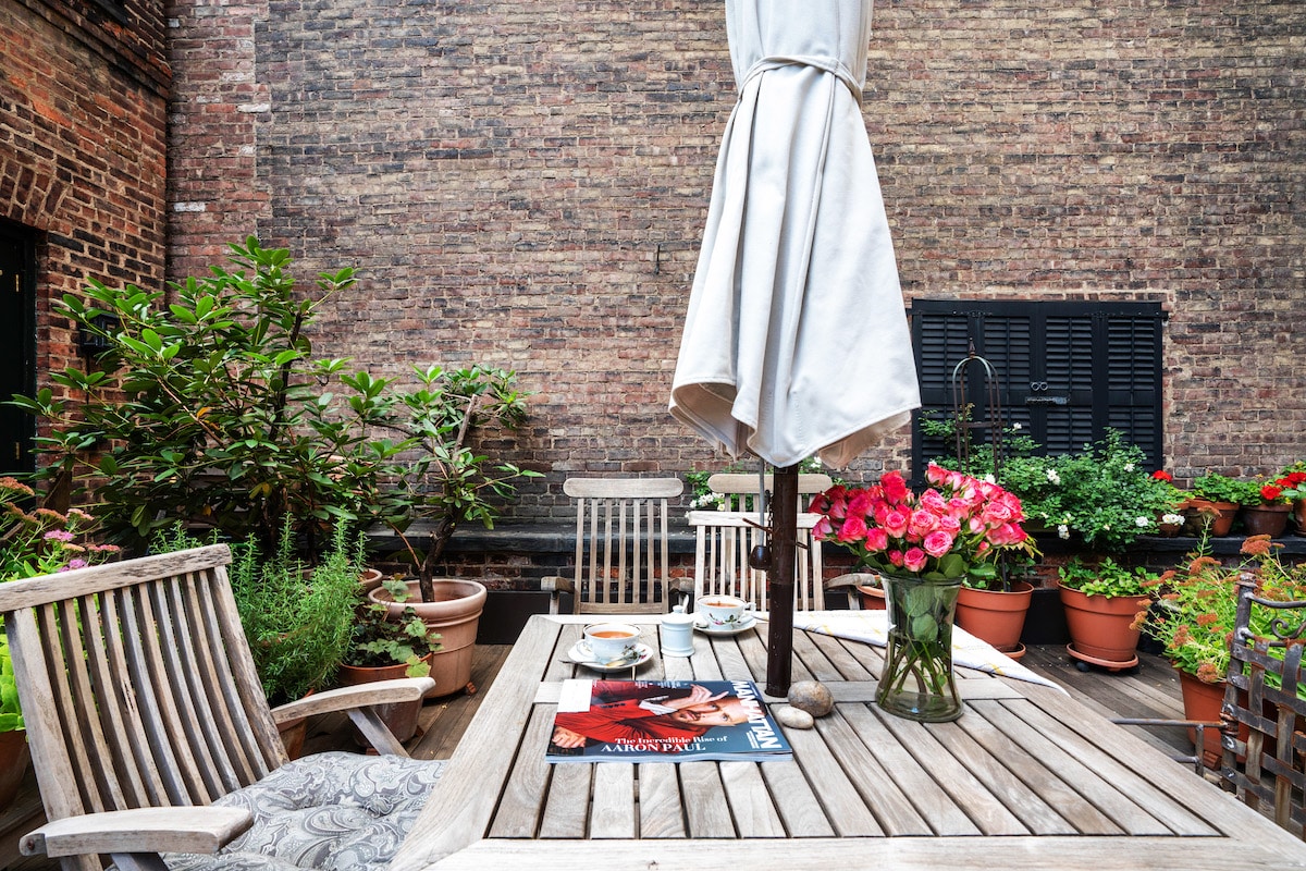 Terrace with wood decking. Teak chairs, large umbrella and plantings.