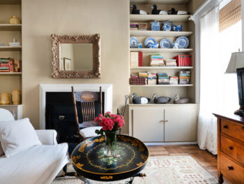 Large Livingroom with loveseat, black oval metal coffee table, beige oriental rug, beige walls, simple fireplace with gold framed mirror above