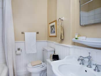 Bathroom with beige walls. Toilet and pedestal sink.