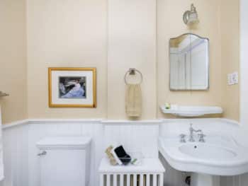 Bathroom with beige walls. Toilet and pedestal sink.