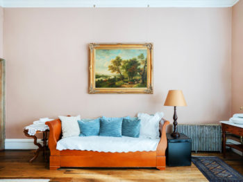 Large bedroom with pink walls. Daybed with white bedspread and blue pillows.