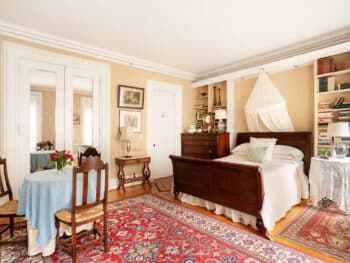 Room with beige walls, red carpets and bed with white coverlet