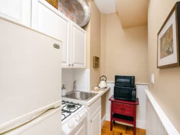 Small kitchen with beige walls, black microwave, red table