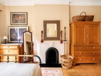 Bedroom with beige walls. Fireplace with mirror above. Oriental Carpet