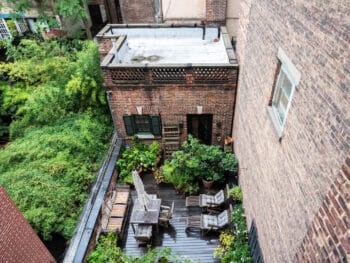 Looking down from back of the apartment is the terrace with lounge chairs, bench and table.