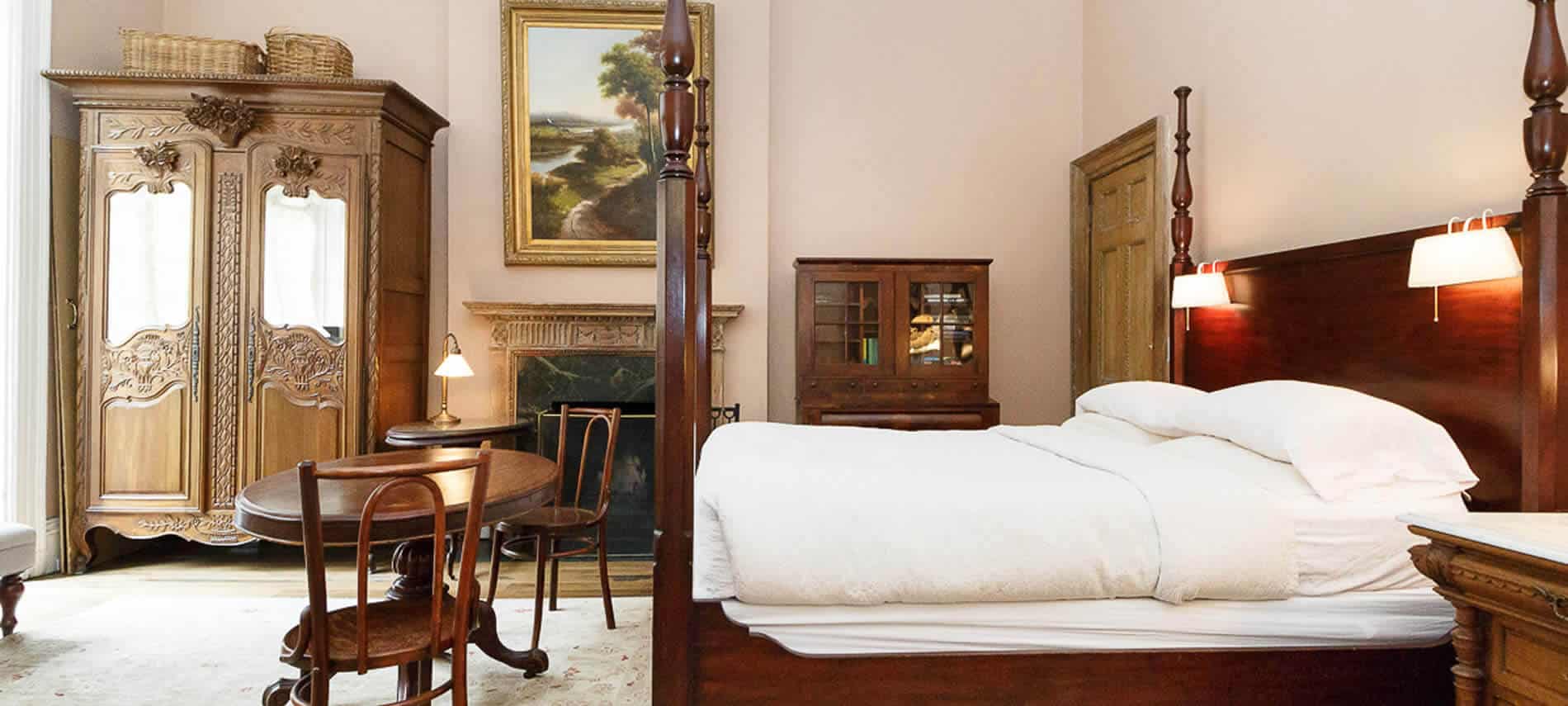 Garden Room At 1871 House Manhattan New York City Side View Of A Pastel Pink Bedroom With Tall Wooden Poster Bed Wood Table